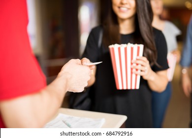 Closeup Of A Woman Holding A Bag Of Popcorn And Handing Her Ticket At The Movie Theater Entrance