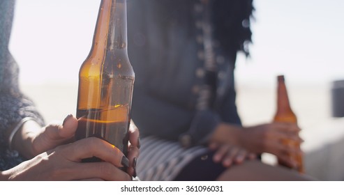 Close-up of woman holding beer bottle with friend in background