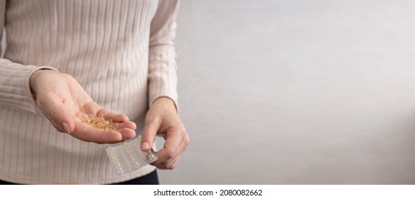 Closeup Woman Holding Capsules And Blister Pack Of Vitamin D Against Bright Wall.Empty Space