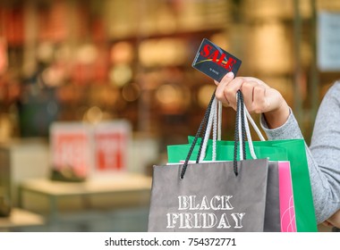Femme en gros plan tenant une carte de crédit et des sacs de courses, concept de vente du Black Friday.
