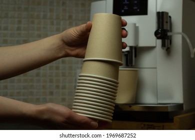 Closeup Of A Woman Holding Disposable Coffee Cups With Coffee Machine In The Background.