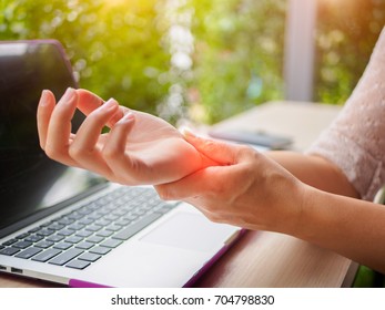 Closeup woman holding her painful hand from using computer. Office syndrome hand pain by occupational disease.