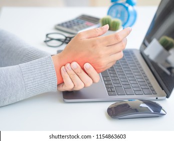 Closeup woman holding her wrist pain from using computer long time. Office syndrome concept.