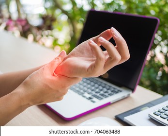 Closeup woman holding her wrist pain from using computer. Office syndrome hand pain by occupational disease.