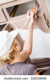 Closeup Of Woman Holding Paint Brush And Painting Kitchen Cabinets