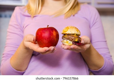 Closeup Woman Holding Red Apple In One Hand And Mini Burger In Other 