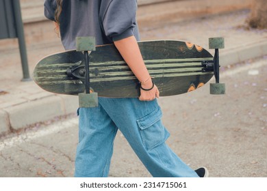 Close-up of a woman holding a skate on the road - Powered by Shutterstock