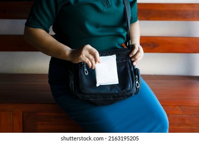 Closeup Woman Holds Sanitary Pad For Menstruation To Put Into Bag Before Going Out. Concept: Female's Hygienic Product For Period's Day. Woman Healthcare. Monthly Intimate Hygiene. 