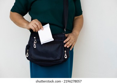 Closeup Woman Holds Sanitary Pad For Menstruation To Put Into Bag Before Going Out. Concept: Female's Hygienic Product For Period's Day. Woman Healthcare. Monthly Intimate Hygiene. 