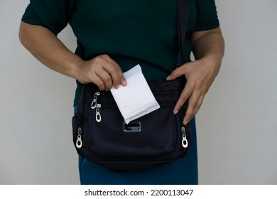 Closeup Woman Holds Sanitary Pad For Menstruation To Put Into Bag Before Going Out. Concept: Female's Hygienic Product For Period's Day. Woman Healthcare. Monthly Intimate Hygiene. 