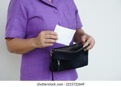 Closeup Woman Holds Sanitary Pad For Menstruation To Put Into Bag Before Going Out. Concept: Female's Hygienic Product For Period's Day. Woman Healthcare. Monthly Intimate Hygiene.                    