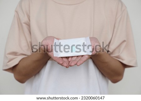  Closeup woman holds sanitary pad napkins.  Concept, female's hygienic product for period's day. Menstruation. Woman healthcare. Monthly intimate hygiene.                                       