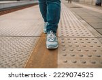  Closeup of woman jeans and sport sneaker shoes walking at the railway station platform.High quality photo