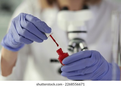 Close-up of woman lab assistant holding bottle of nail polish in hands. chemical analysis concept