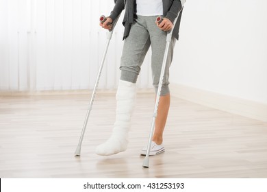 Close-up Of Woman Leg In Plaster Cast Using Crutches While Walking