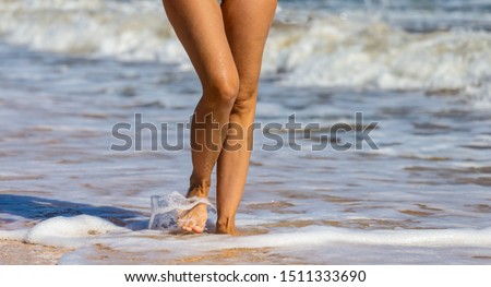 closeup woman legs on a sea waves background, summer sea beach vacation scene