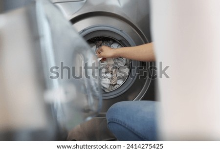 Close-up of woman loading washing machine with dirty clothes, taking out clean stuff. Household, bathroom, domestic chores, cleaning day, housewife concept