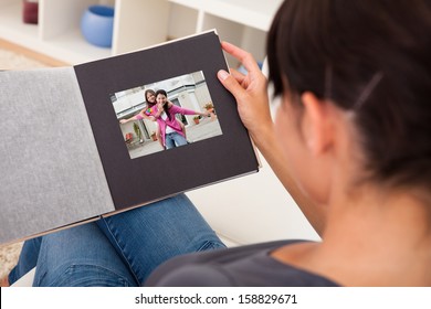 Close-up Of Woman Looking Through Photo Album; Indoors