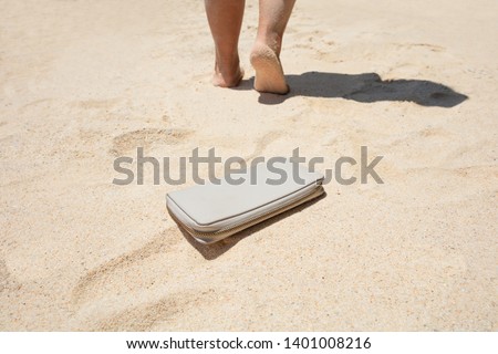Close-up Of A Woman Lost A Purse With Money On The Sandy Beach