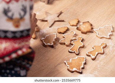 Close-up of woman Making homemade Christmas cookies, decorating gingerbread man and trees at wooden table. Copy space - Powered by Shutterstock