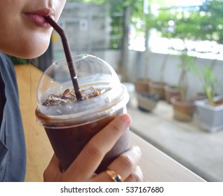 closeup woman mouth drinks ice coffee in the coffee at the window with soft light.