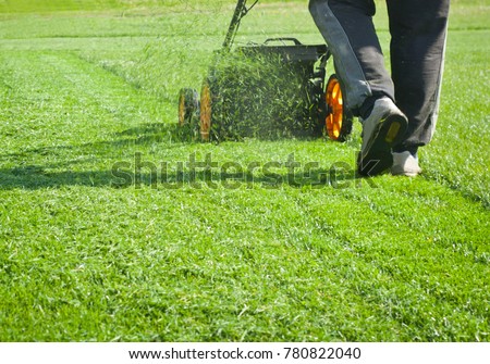 Closeup of a woman mowing the grass with lawn mower.