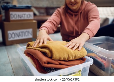 Close-up of woman packing donation box with clothes for people in need. - Shutterstock ID 2140619391