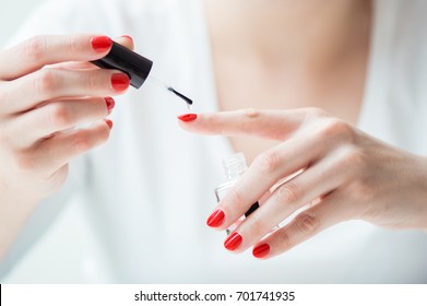 Closeup of a woman painting her nails with transparent nail polish - Powered by Shutterstock