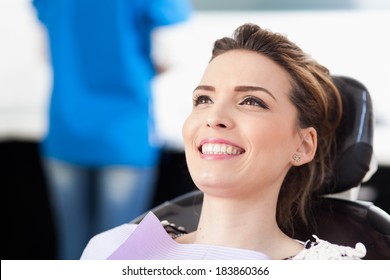 Closeup of a woman patient at the dentist waiting to be checked up with the woman doctor in the background - Powered by Shutterstock