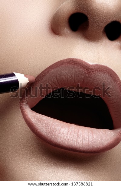 Closeup of woman plump lips with lip liner.\
Professional make-up artist applying lips liner for perfect make-up\
contour. Fashion makeup
