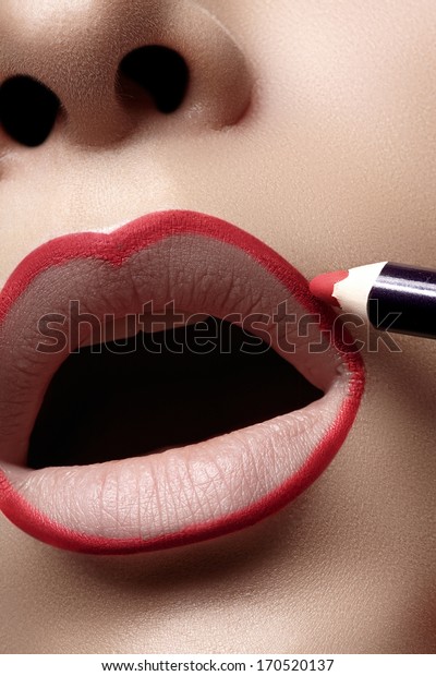 Closeup of woman plump lips with lip liner. Professional\
make-up artist applying lips liner for perfect make-up contour.\
Fashion makeup 