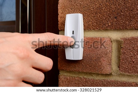 Close-up of woman pressing the button of a doorbell on a brick wall