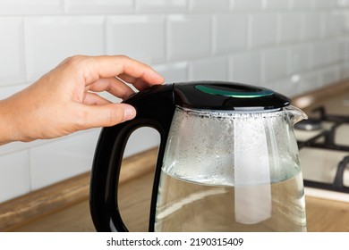 Close-up Of A Woman Pressing The Power Switch On An Electric Kettle.Kettle For Boiling Water And Making Tea.Home Appliances For Making Hot Drinks.Space For Copy.Place For Text.