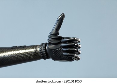 Close-up Of Woman With Prosthetic Arm Showing Thumb Up Isolated On Blue Background