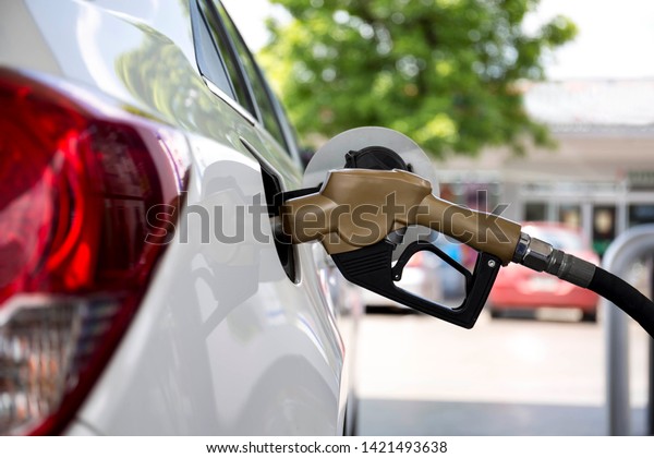 Closeup\
of woman pumping gasoline fuel in car at gas station. Petrol or\
gasoline being pumped into a motor vehicle\
car.