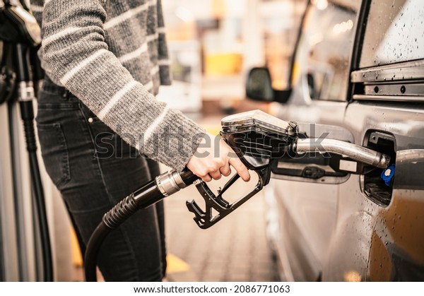 Closeup of woman pumping gasoline fuel in car at\
gas station. Petrol or gasoline being pumped into a motor.\
Transport concept