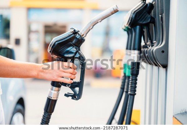 Closeup of woman pumping gasoline fuel in car at\
gas station. Petrol or gasoline being pumped into a motor.\
Transport concept
