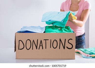 Close-up Of A Woman Putting Clothes Inside Donation Box