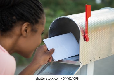 Close-up Of Woman Putting Letter In Mailbox