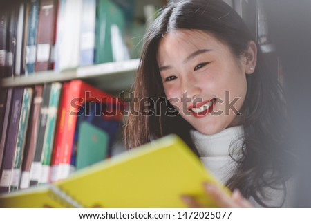 Close-up woman reading a book in library, Portrait girl reading a book  library bookshelves, Back to school concept