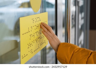 Close-up of a woman reading a braille lettering on a glass door. - Powered by Shutterstock