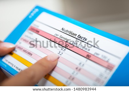 Close-up Of Woman Reading Nutrition Facts On Box