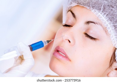 closeup of woman receiving cosmetic injection through nose isolated on white