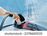 Closeup woman recharge EV electric car battery at charging station connected to electrical power grid tower on sky background as electrical industry for eco friendly vehicle utilization. Expedient