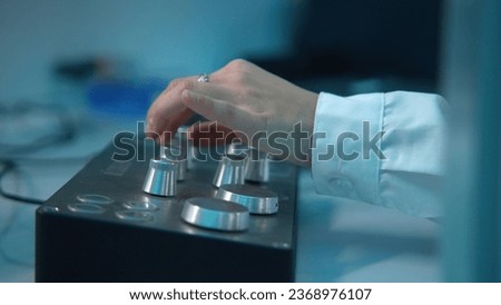 Close-up of woman rotating buttons on equipment control panel. Stock footage. Woman turns buttons on panel of laboratory equipment. Equipment with buttons in scientific laboratory