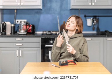Close-up of woman sharpening knife with special knife sharpener at home