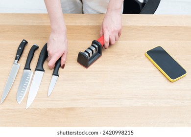 Close-up of woman sharpening knife with special knife sharpener at home	 - Powered by Shutterstock