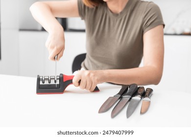 Close-up of woman sharpening knife with special knife sharpener at home	 - Powered by Shutterstock