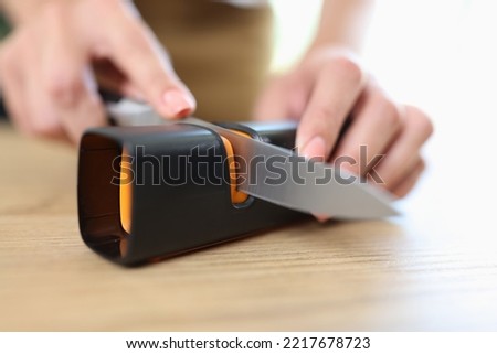 Close-up of woman sharpening knife with special knife sharpener. Grindstone, kitchen tools and devices concept