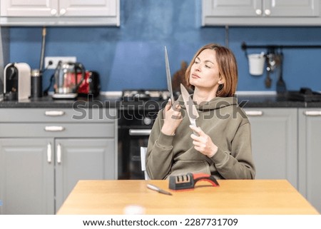 Close-up of woman sharpening knife with special knife sharpener at home